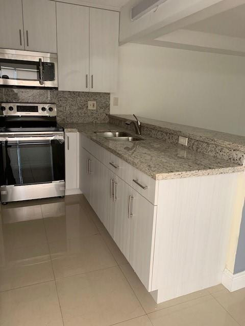 1950 Southwest 121st Court, Unit 240 Miami, FL 33175 - Photo 7 of 27 a kitchen with granite countertop a sink a stove and cabinets