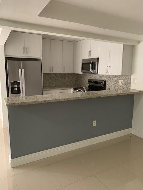 1950 Southwest 121st Court, Unit 240 Miami, FL 33175 - Photo 10 of 27 a kitchen with stainless steel appliances a sink a stove a microwave and white cabinets