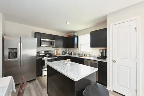 a kitchen with kitchen island granite countertop stainless steel appliances cabinets a sink and a counter space