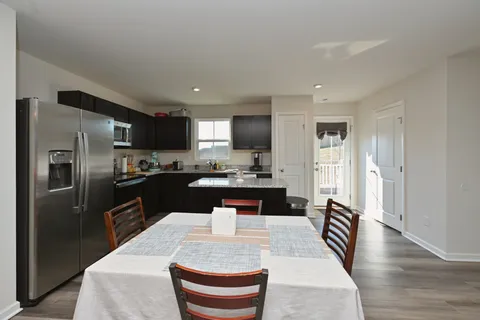 a living room with stainless steel appliances kitchen island granite countertop a refrigerator a stove a sink a washer and dryer with wooden floor