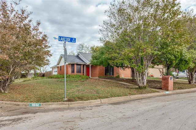 a view of a house with a yard and large tree