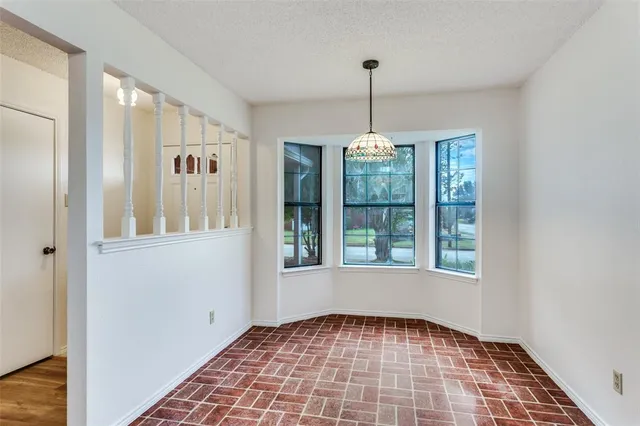 a view of an empty room with window and chandelier fan