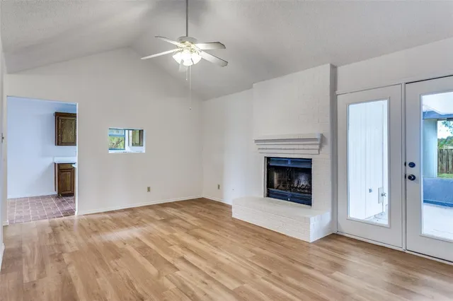 a view of an empty room with wooden floor fireplace and a window