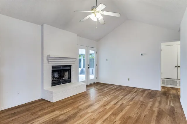 a view of an empty room with chandelier fan and fire place