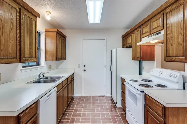 a kitchen that has a sink a stove and a refrigerator