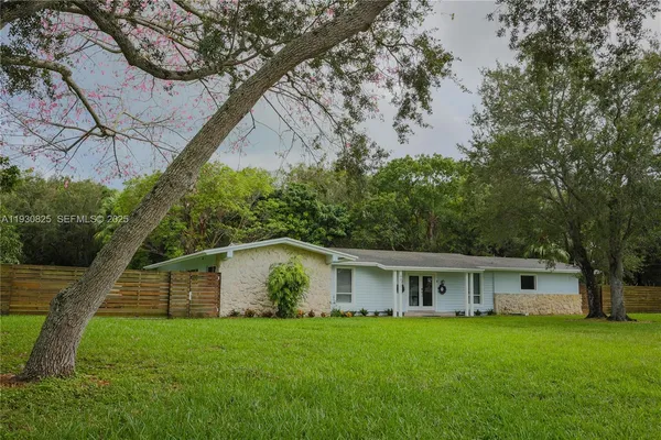 a front view of a house with a garden and trees
