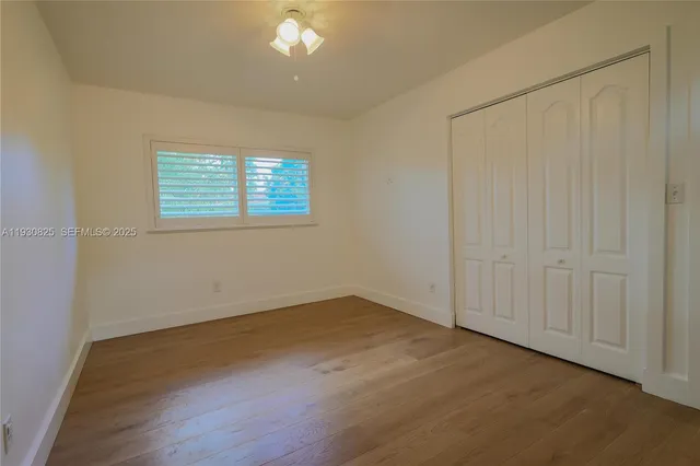 an empty room with wooden floor and windows with curtains