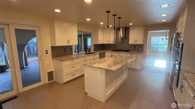 a kitchen with stainless steel appliances kitchen island granite countertop a refrigerator and a sink