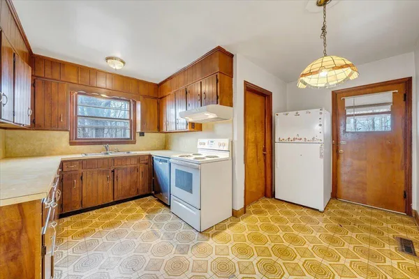 a large kitchen with a stove a refrigerator a sink dishwasher and wooden cabinets