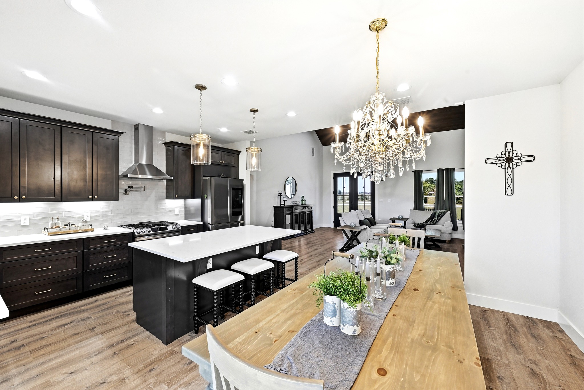 2889 Old McMahan Road Lockhart, TX 78644 - Photo 12 of 33 A striking chandelier illuminates the spacious kitchen and dining area, flowing seamlessly into the inviting living space.