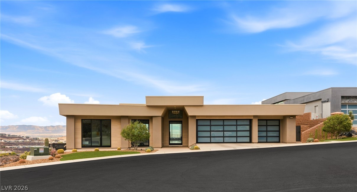 677 Overlook Rim Drive Henderson, NV 89012 - Photo 2 of 97 Clean modern architectural lines frame this desert residence featuring glass garage doors and panoramic mountain views.