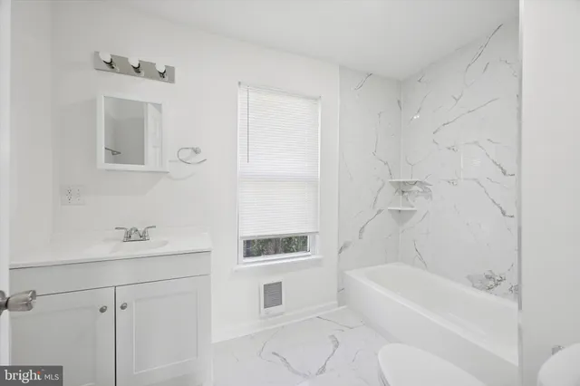 a bathroom with a bathtub shower sink vanity and toilet