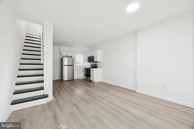 a view of kitchen with wooden floor electronic appliances and stairs