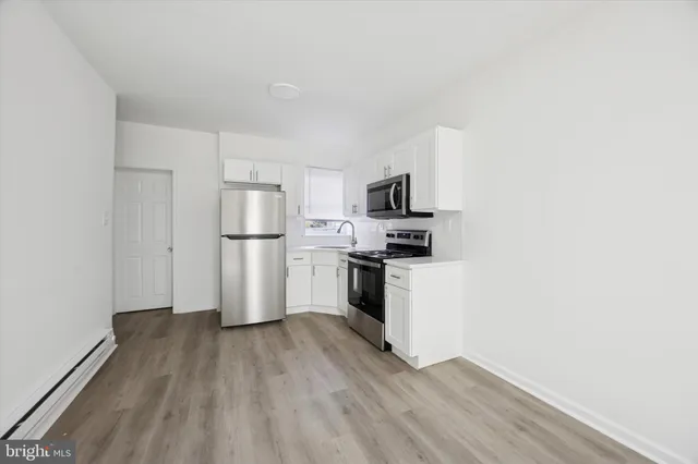 a kitchen with wooden floors white cabinets and stainless steel appliances