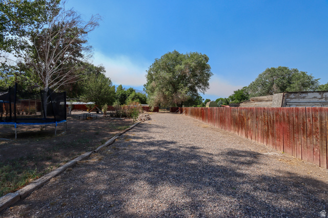 270 East 100 North Monroe, UT 84754 - Photo 34 of 65 Expansive gravel pathway bordered by a red-stained wooden fence and mature trees