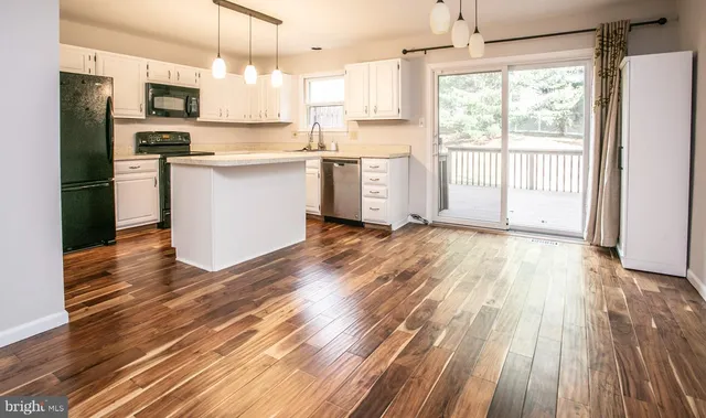 a kitchen with stainless steel appliances granite countertop a refrigerator a sink dishwasher a stove and white countertops with wooden floor