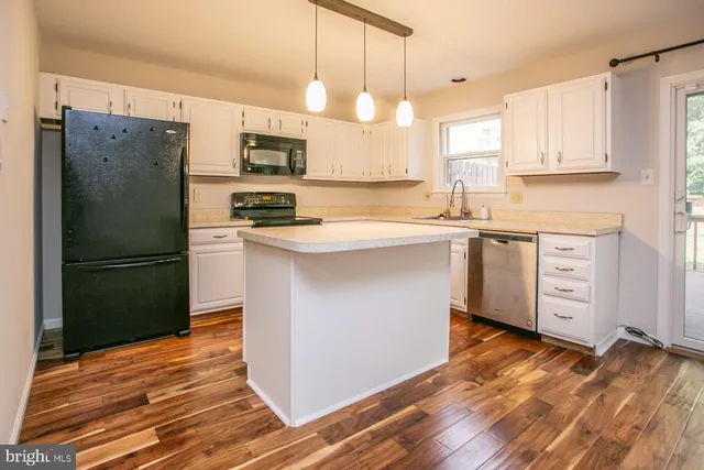 a kitchen with stainless steel appliances granite countertop a refrigerator a sink dishwasher a stove and white countertops with wooden floor