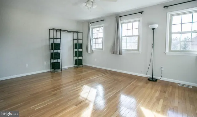 an empty room with wooden floor and windows