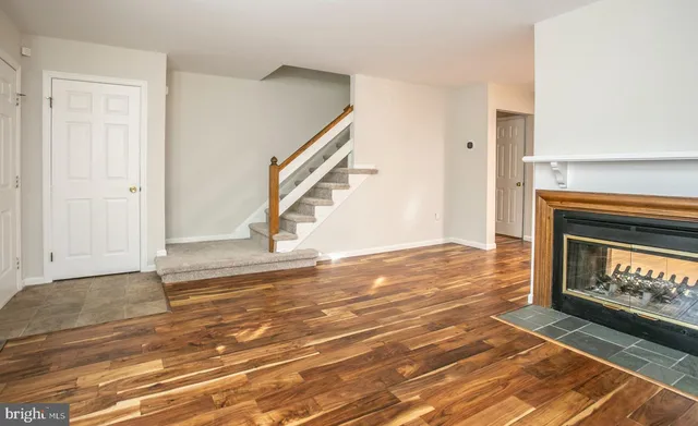 a view of an empty room with wooden floor fireplace and a window