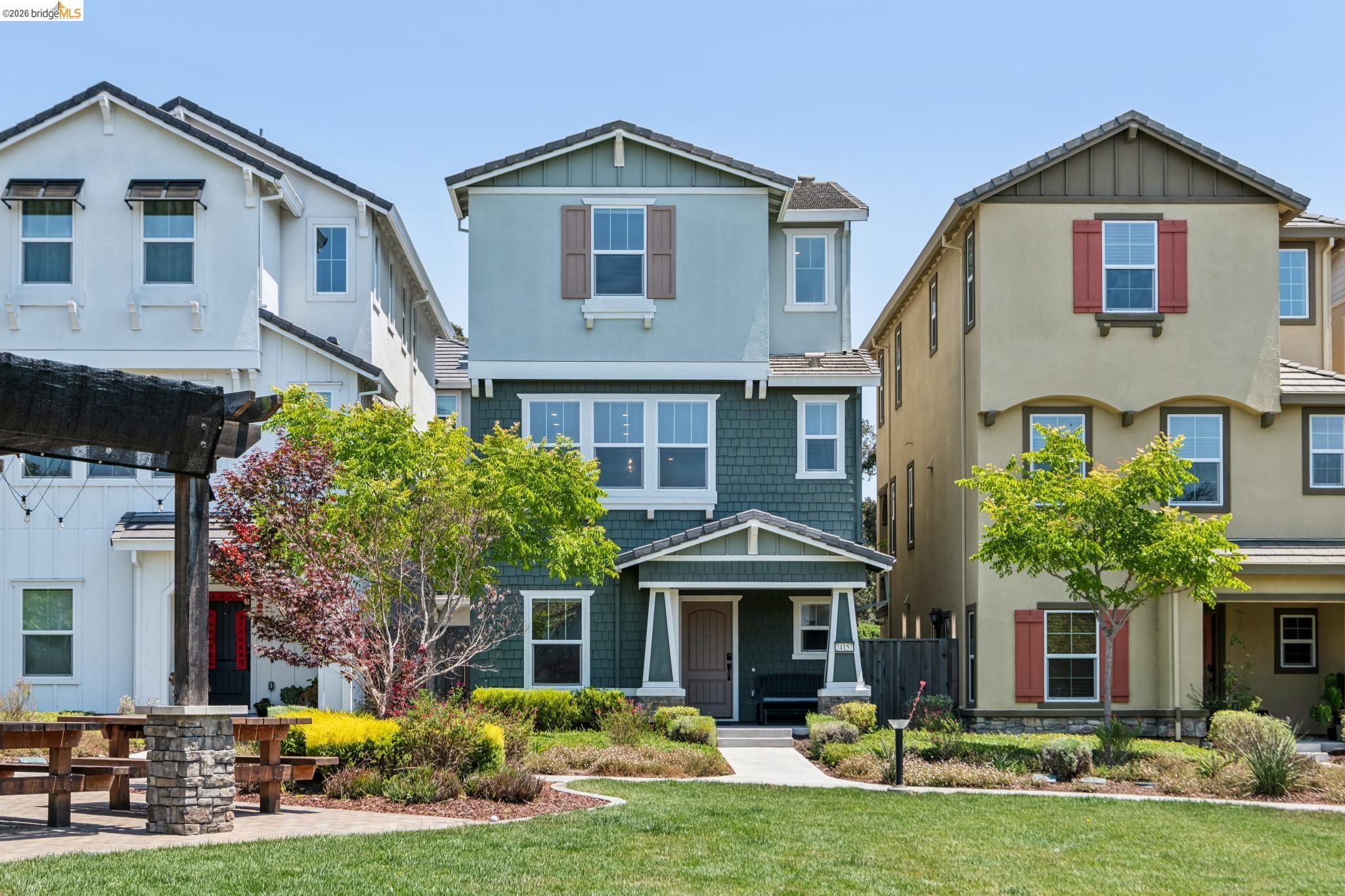 Three-story property featuring a multi-toned exterior with shingle and horizontal siding, a covered entry porch, and decorative window shutters