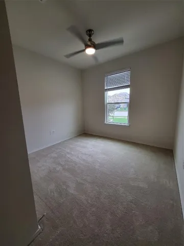 an empty room with a window and a ceiling fan