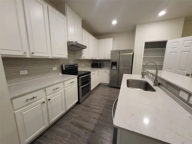 a kitchen with stainless steel appliances granite countertop a sink a stove and a refrigerator