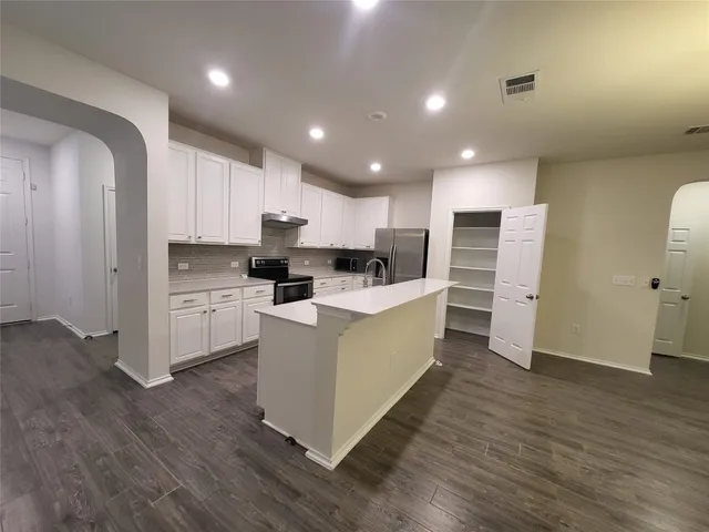 a large kitchen with cabinets and wooden floor