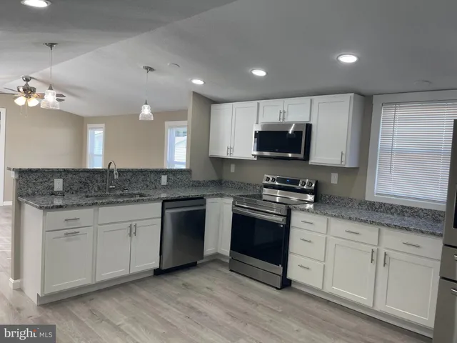 a kitchen with granite countertop a stove a sink and a microwave