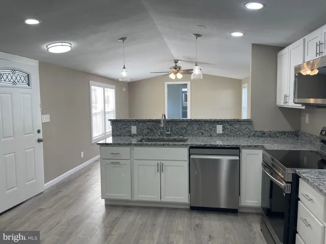 a kitchen with stainless steel appliances granite countertop a sink a stove a refrigerator and a microwave