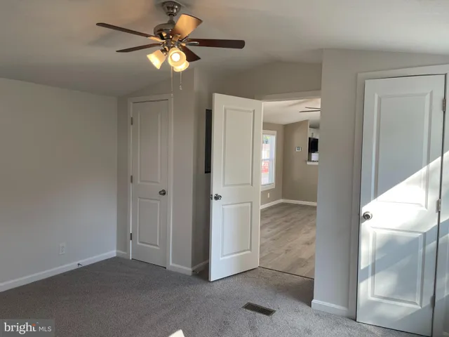 a view of a livingroom with a chandelier fan and windows