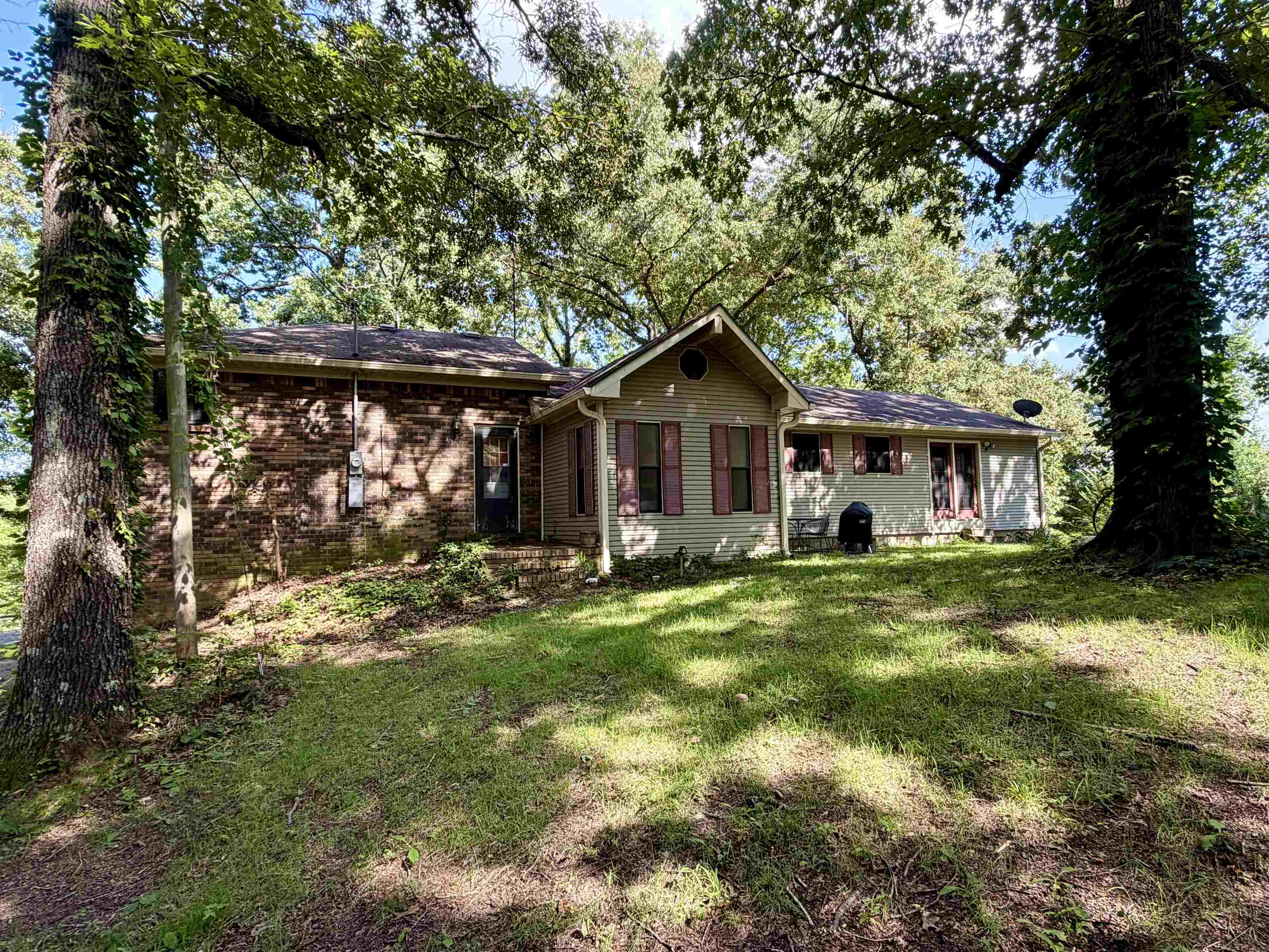 373 Clarence Barham Road Bethel Springs, TN 38315 - Photo 22 of 28 Exterior residential property featuring a combination of brick and siding finishes, a pitched roof, and mature trees providing natural shade