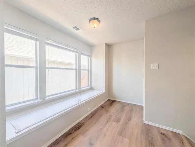 an empty room with wooden floor cabinet and windows