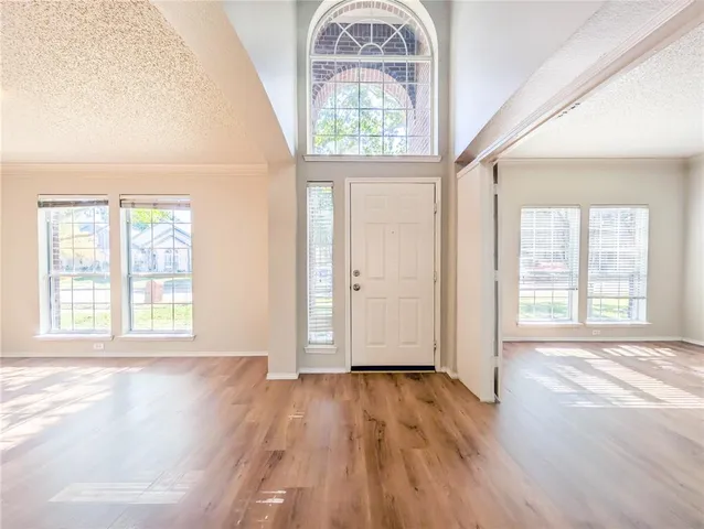 an empty room with wooden floor windows and entrance