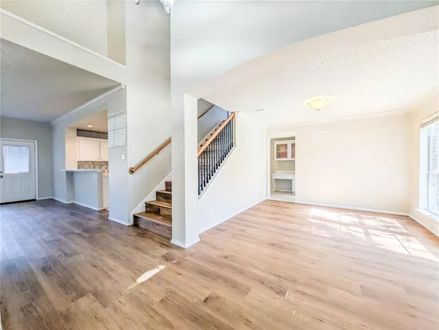a view of an empty room with wooden floor and stairs