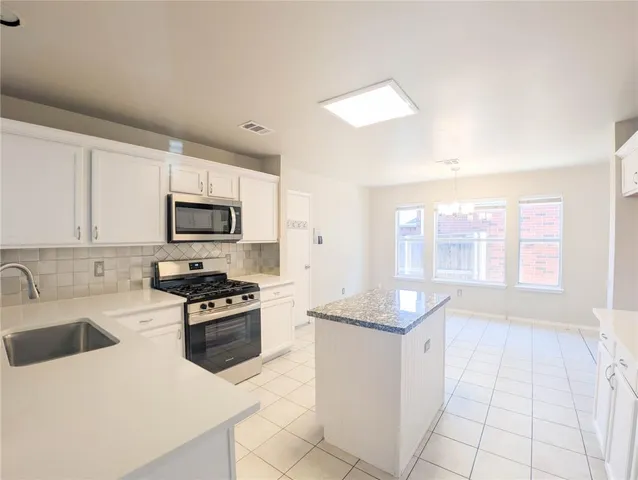 a kitchen with a refrigerator and white cabinets
