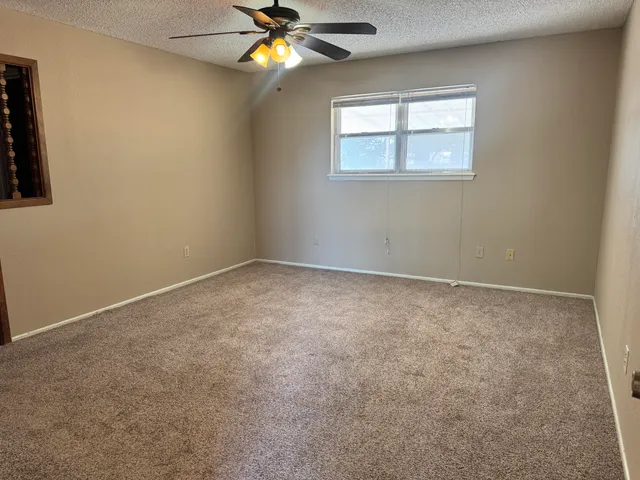 an empty room with windows and fan