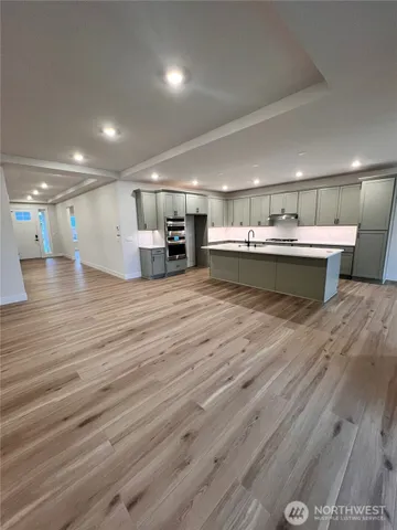 a view of a room with kitchen island stainless steel appliances wooden floor and window