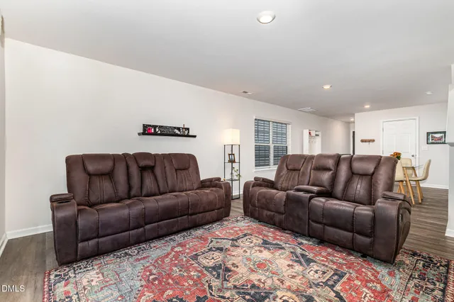 a living room with furniture a wooden floor and next to a window