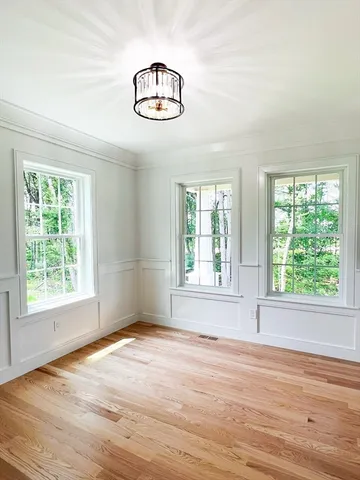 an empty room with wooden floor fan and windows
