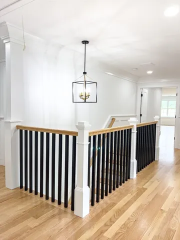 a view of a hallway with wooden floor and staircase