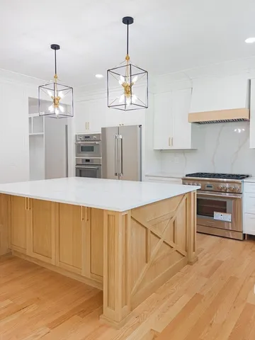 a kitchen with stainless steel appliances kitchen island granite countertop a stove a sink dishwasher and a refrigerator with wooden floor