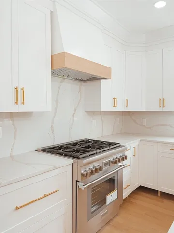 a kitchen with granite countertop a stove and a white cabinets