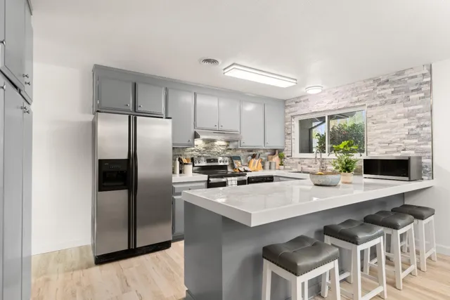 a kitchen with a sink a refrigerator and chairs