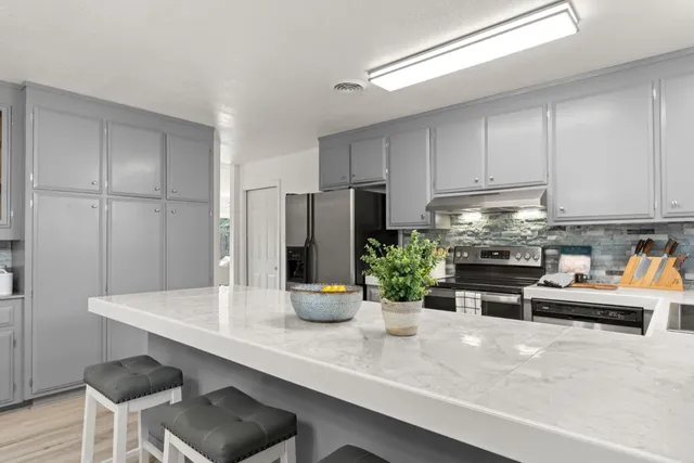 a kitchen with stainless steel appliances a dining table chairs refrigerator and cabinets