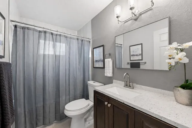 a bathroom with a granite countertop sink toilet and shower