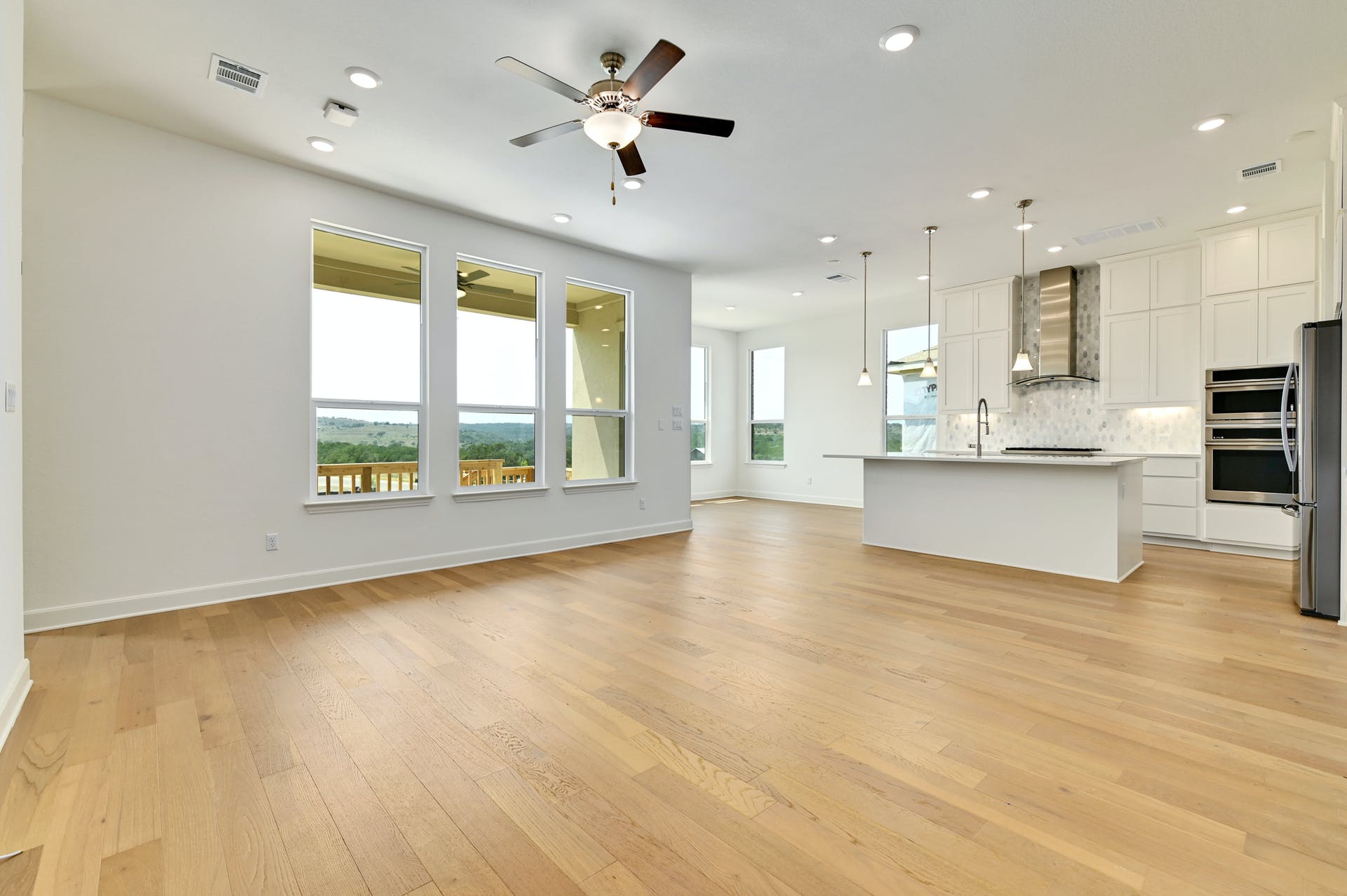 19005 Fernando Trail Austin, TX 78738 - Photo 9 of 35 Open living room with large windows, light wood finished floors, a ceiling fan, and recessed lighting