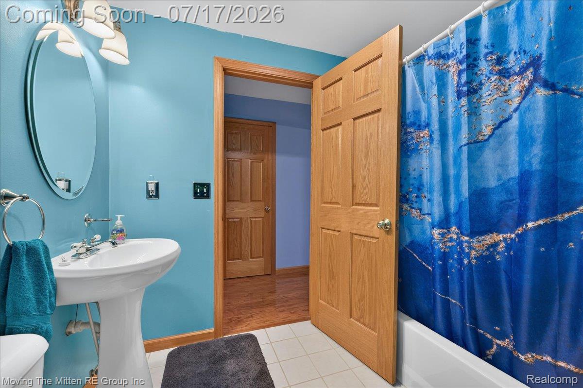 40162 Alden Road Belleville, MI 48111 - Photo 34 of 67 Bathroom featuring a white pedestal sink with polished chrome fixtures, an oval wall-mounted mirror, and a full-size bathtub with shower capabilities
