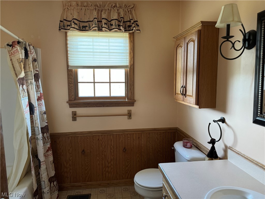 2812 Tabor Ridge Road Northeast Mineral City, OH 44656 - Photo 14 of 23 Full bathroom featuring shower / bathtub combination with curtain, toilet, tile flooring, wooden walls, and vanity