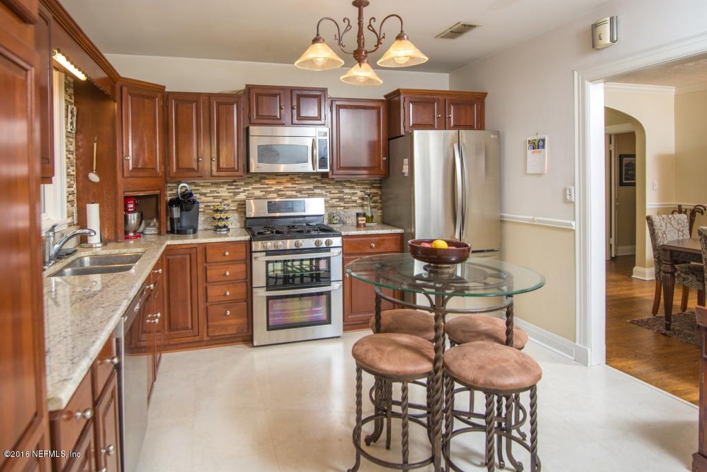 1128 Greenridge Road Jacksonville, FL 32207 - Photo 16 of 37 a kitchen with stainless steel appliances wooden cabinets dining table and chairs