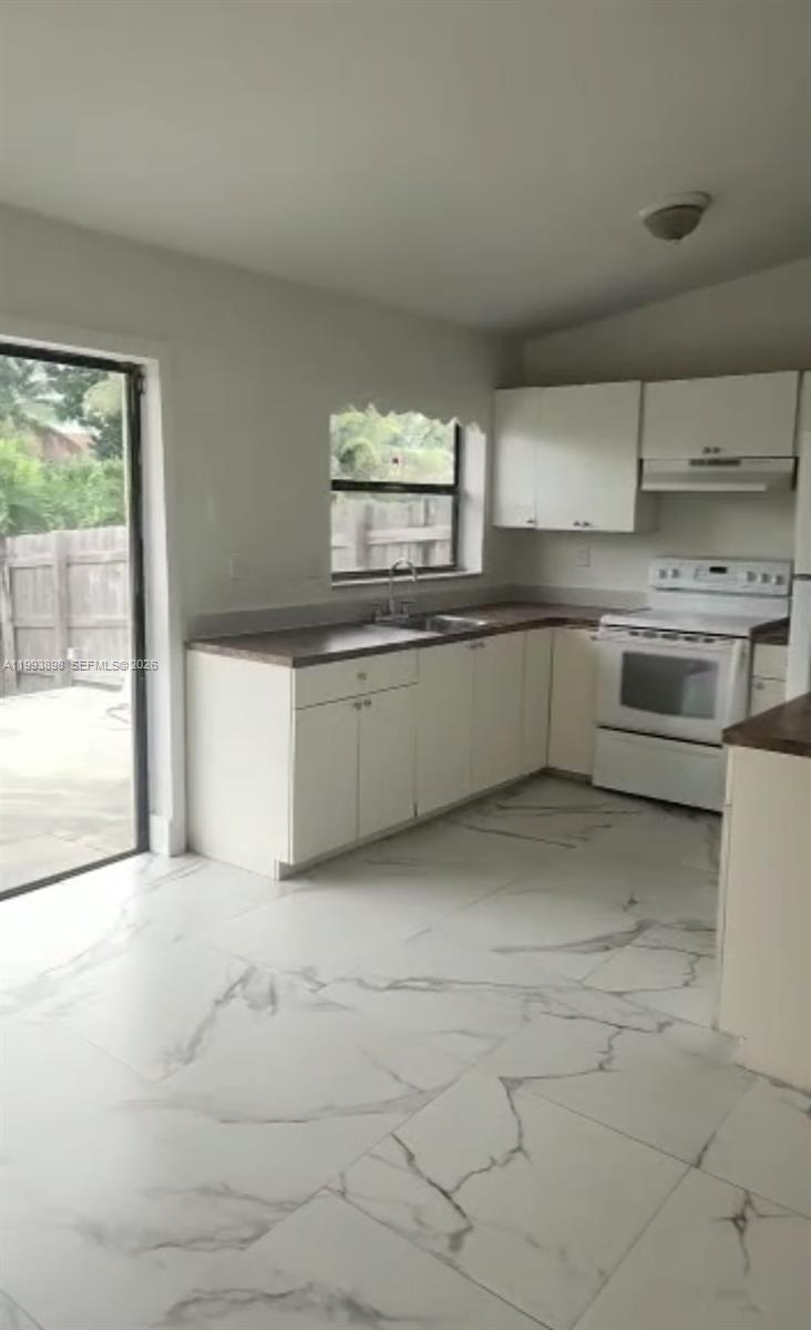 13949 Southwest 281st Terrace, Unit 13949 Homestead, FL 33033 - Photo 4 of 11 a large white kitchen with granite countertop a sink and white cabinets